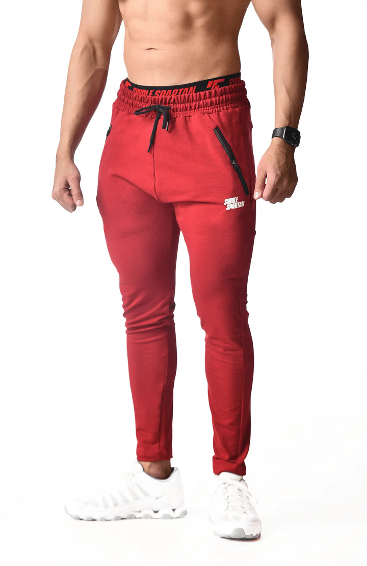  A man dressed in red sweatpants and white sneakers stands confidently, showcasing a casual and sporty style.