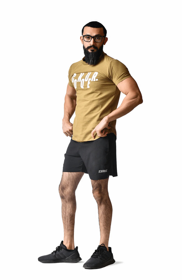 A bearded man wearing a gold t-shirt, showcasing a casual and stylish appearance.