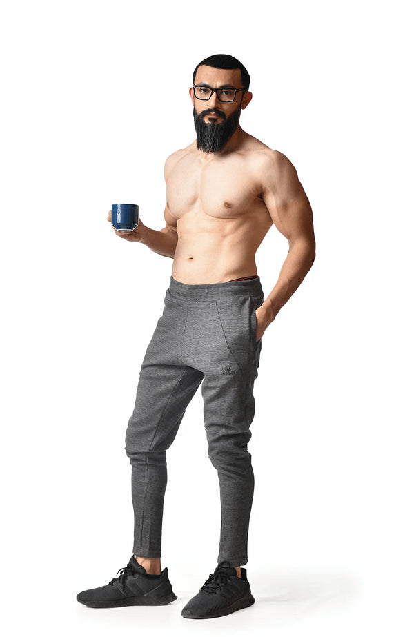 A shirtless man stands holding a cup of coffee, enjoying a moment of relaxation in a casual setting.